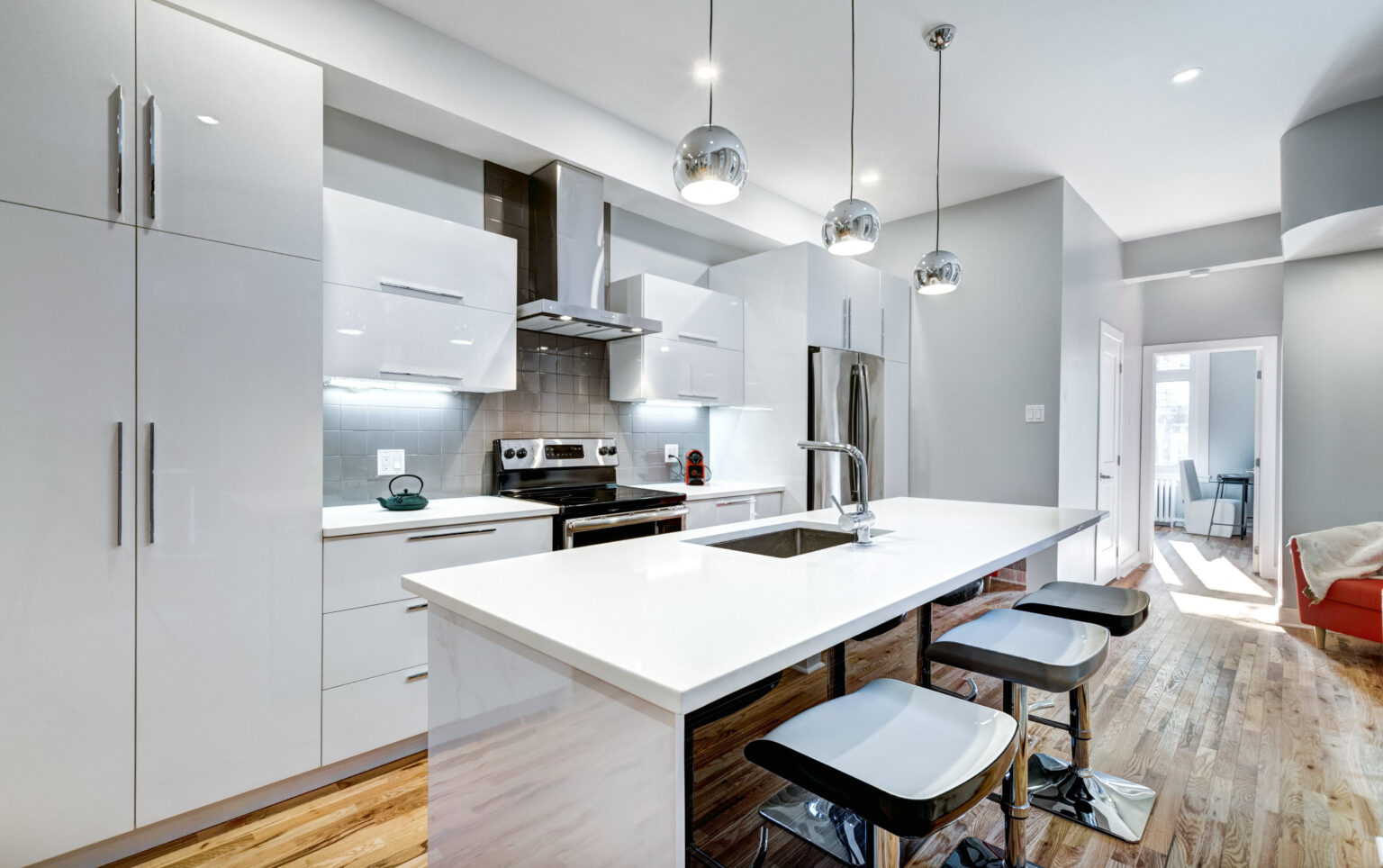 Cocina lineal reformada con encimera de cuarzo y muebles blancos.